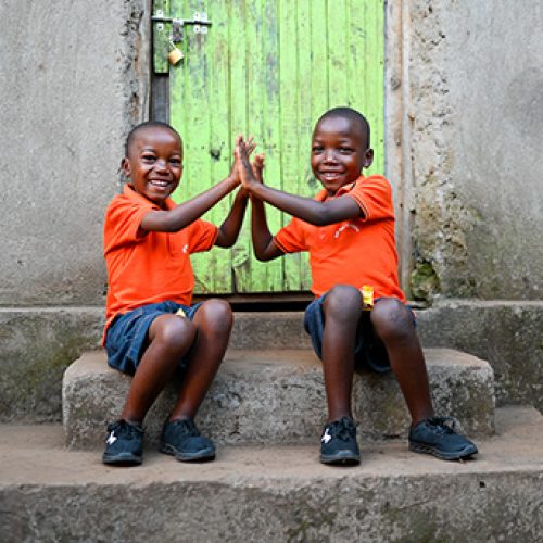 Twee jongens uit Rwanda geven elkaar een high five.