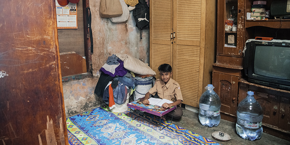 Agung uit Indonesië maakt huiswerk in de woonkamer.