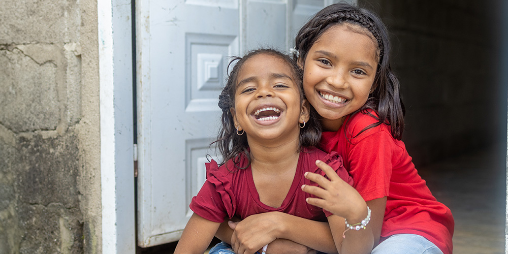 Sofy uit Colombia zit in de deuropening met haar zusje.