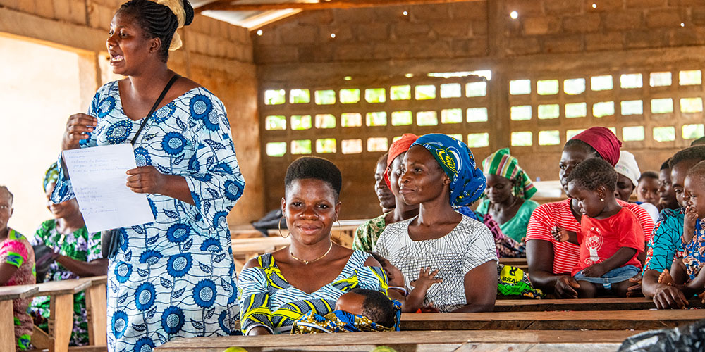 Davi uit Togo luistert met haar baby op schoot naar een les in het Moeder- en babyprogramma.