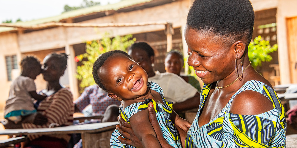 Davi uit Togo houdt haar dochter Yawa lachend vast.