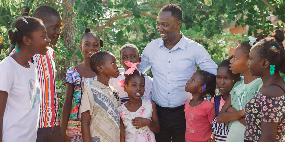 Projectdirecteur John uit Haïti met kinderen om zich heen.