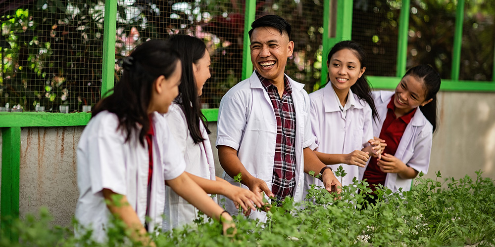 Frizky uit Indonesië staat in zijn hydrocultuurtuin met andere jongeren om zich heen.