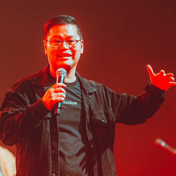 Gilbert Thera staat op een podium en vertelt over Compassion.