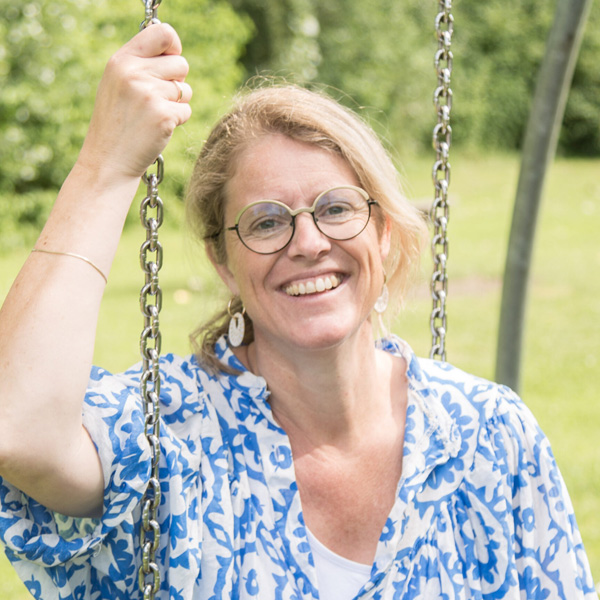 Cootje van de Wetering zit op een schommel en kijkt lachend in de camera.