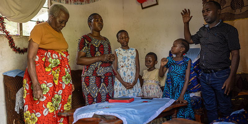 Een gezin uit Tanzania bidt in hun huis.