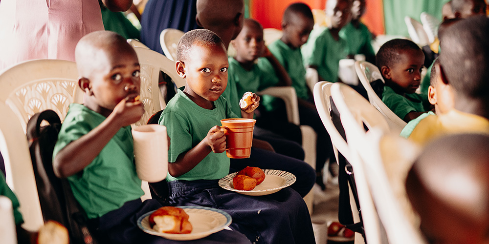 Kinderen eten mandazi op een Compassion-project in Rwanda.