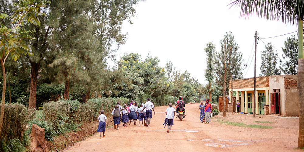 Kinderen lopen in hun schooluniform over een weg in Rwanda.