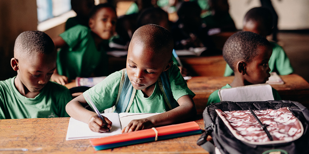 Een kind schrijft een brief op een Compassion-project in Rwanda. 