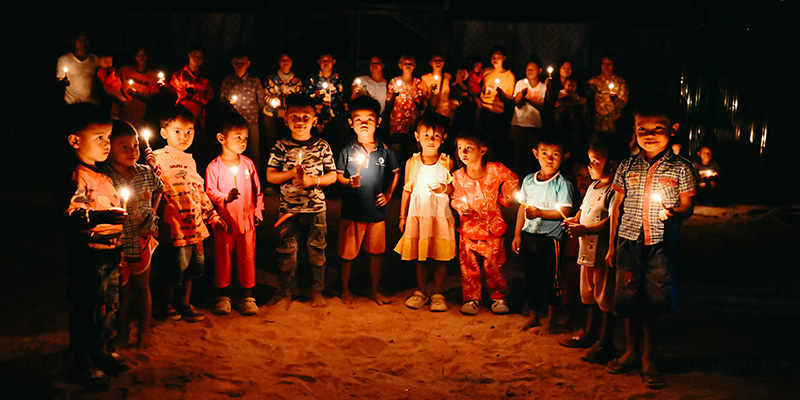 Kinderen uit Cambodja luisteren bij kaarslicht naar het kerstverhaal.
