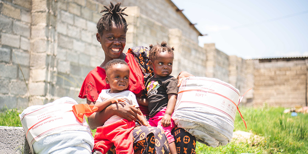Sarah uit Zambia zit met haar tweeling Towela en Daniel op schoot.