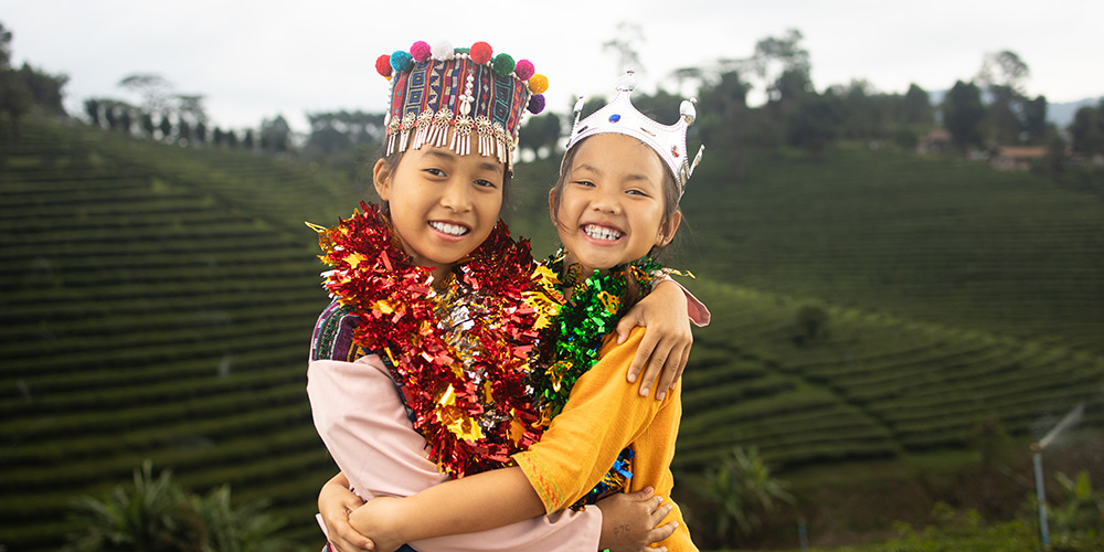 Twee meisjes uit Thailand kijken lachend in de camera.