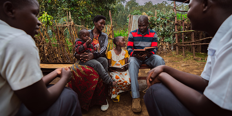 Het gezin van Annette uit Rwanda doet buiten een Bijbelstudie.