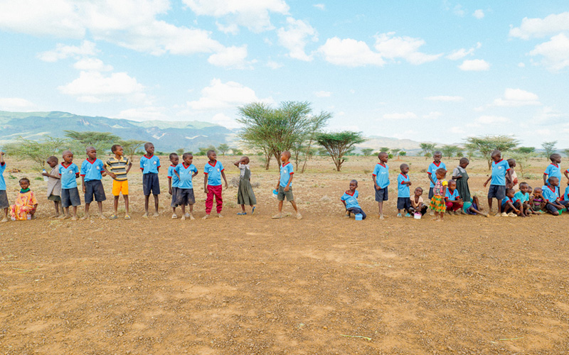 Een groep kinderen staat langs de kant van de weg.