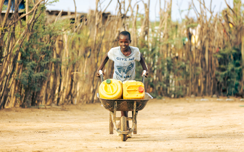 Auru uit Kenia brengt met een kruiwagen water in grote gele jerrycans naar huis.
