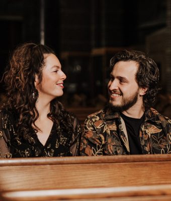 Artiesten Peeber en Maaike zitten in een kerkbank.