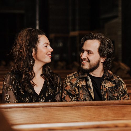 Artiesten Peeber en Maaike zitten in een kerkbank.