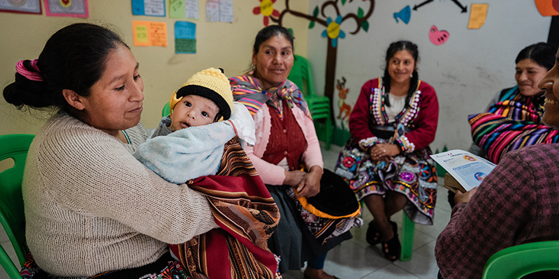 Een groep moeders uit Peru zitten in een kring in het Moeder-en babyprogramma.