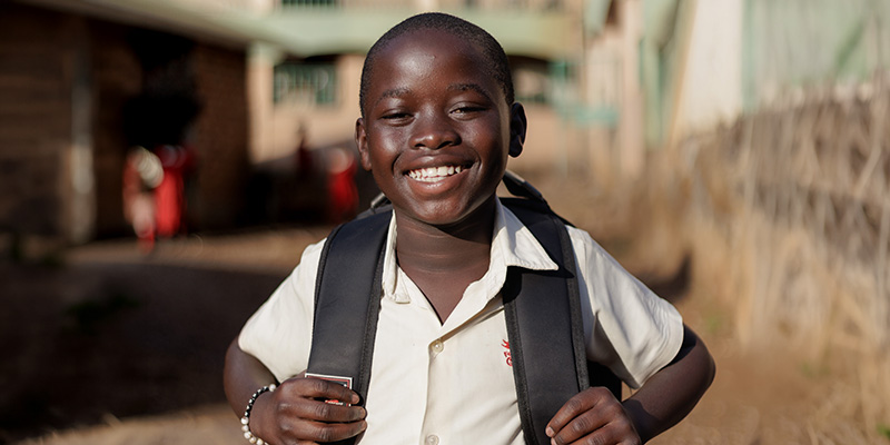 Jordan uit Uganda kijkt lachend in de camera.