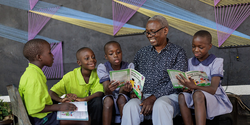 Pastor Paul uit Uganda zit samen met een groep kinderen in de kerk.