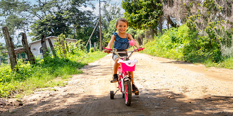 Maydelin uit Honduras fietst met haar roze fiets over de weg.