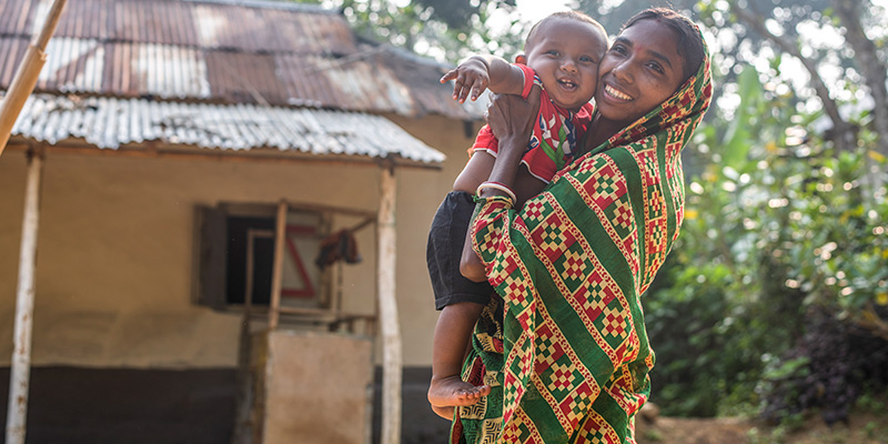 Moeder Janata uit Bangladesh tilt baby Johan op. 