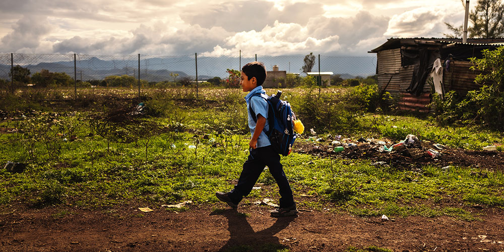 Anderson uit Guatemala loopt over een onverharde weg naar school.