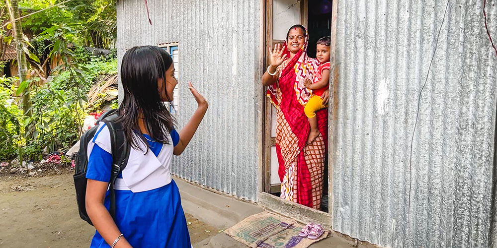 Anonna uit Bangladesh zwaait naar haar moeder en broertje.