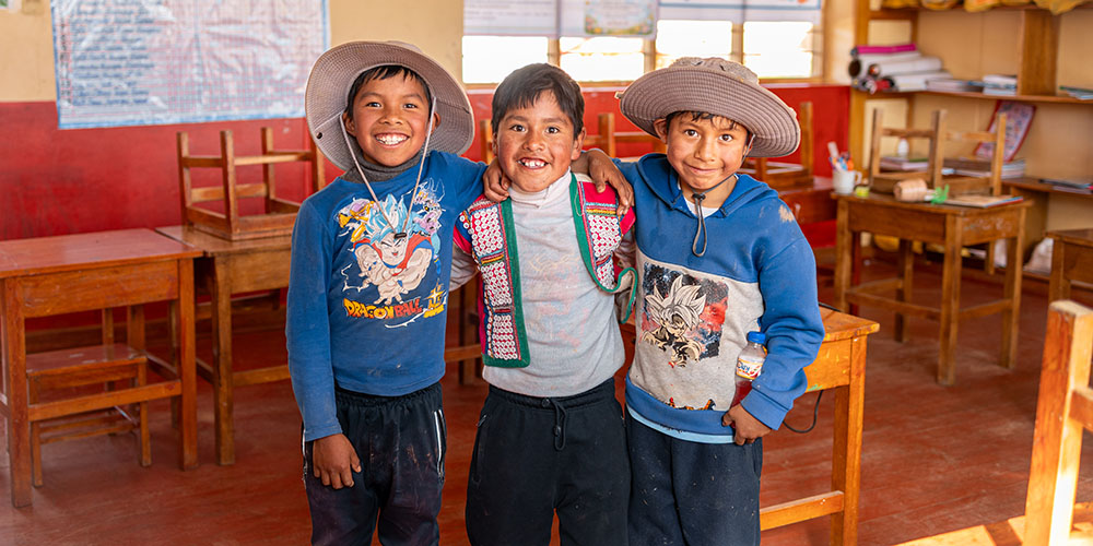 Armando uit Peru staat in een klaslokaal tussen zijn vrienden.