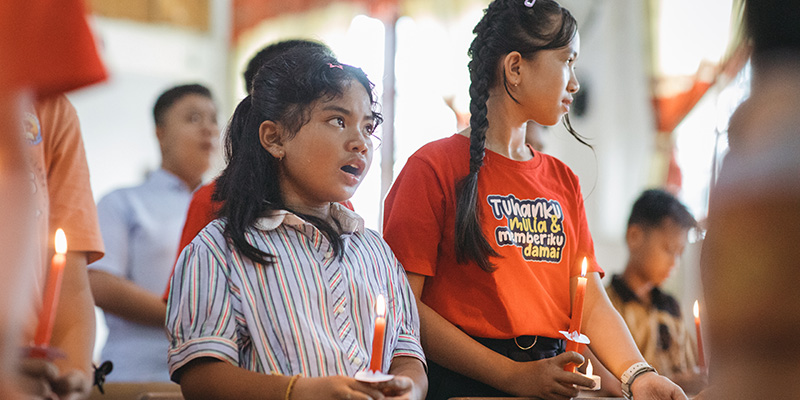 Ima uit Indonesië houdt een kaars vast tijdens de kerstviering op het Compassion-project. 