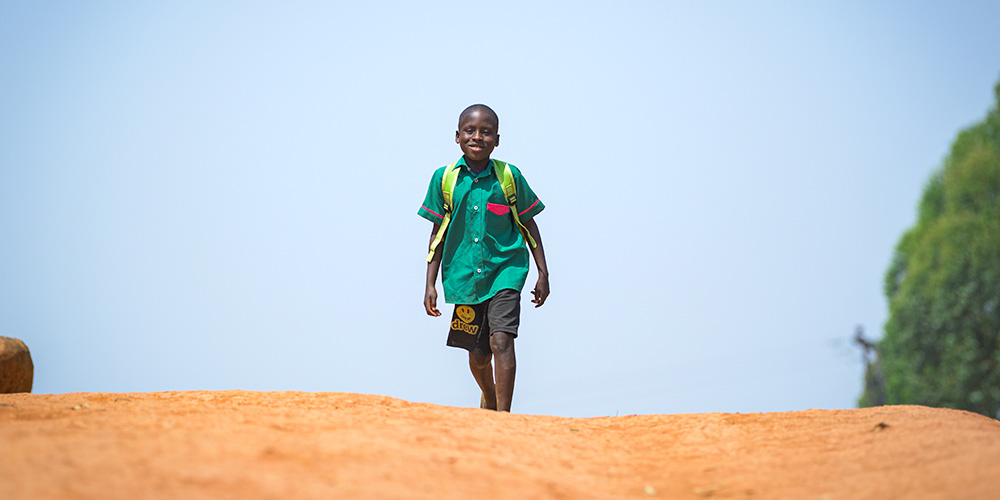 Kelvin uit Malawi loopt in zijn schooluniform naar school.