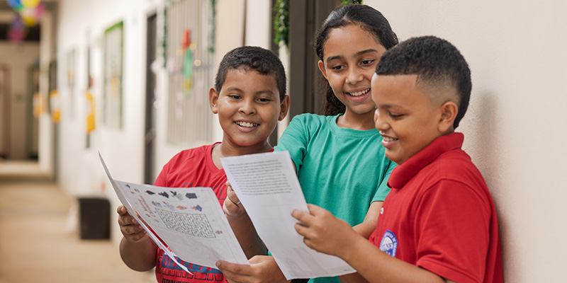 Wilber, Kiara en Farid uit Colombia lezen hun kerstkaart.